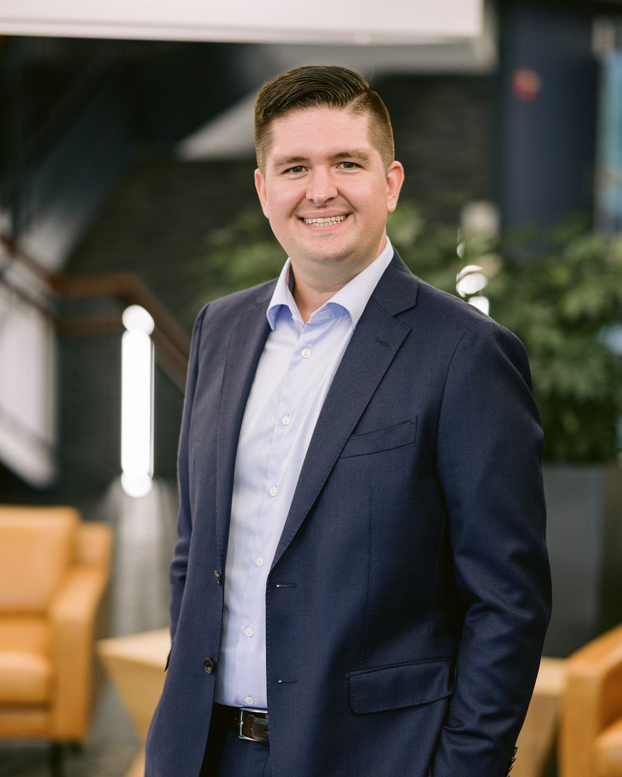 Dr. Josh Bednar standing in a navy suit and light blue shirt