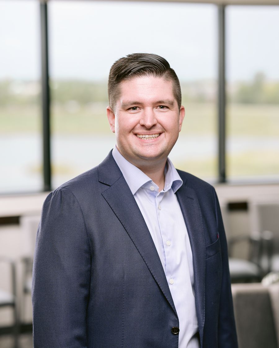 Dr. Josh Bednar smiling in a navy blazer in front of a large window